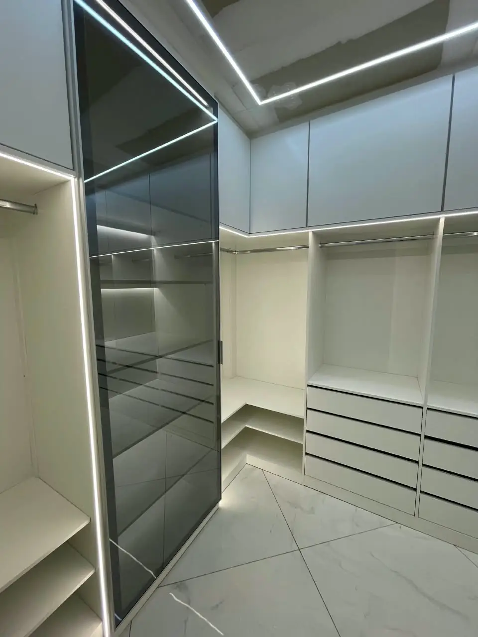 Closet planejado branco com porta de vidro fumê e iluminação de LED